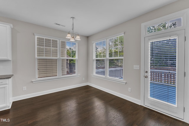 unfurnished dining area featuring a chandelier, visible vents, baseboards, and dark wood-style flooring