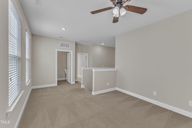 spare room featuring plenty of natural light, visible vents, and light colored carpet