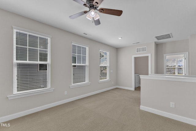 empty room featuring visible vents, a wealth of natural light, and light colored carpet