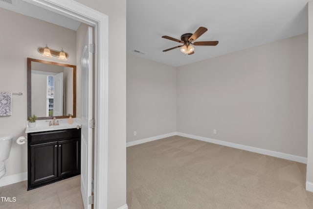 bathroom with visible vents, toilet, vanity, baseboards, and ceiling fan