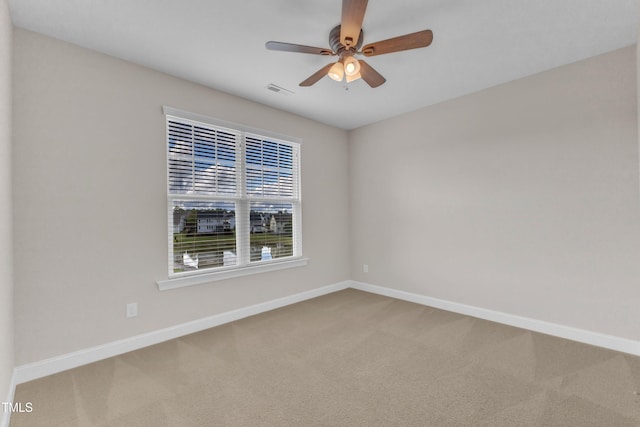 carpeted spare room with visible vents, baseboards, and ceiling fan
