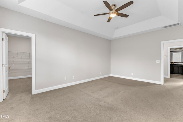 unfurnished bedroom featuring a raised ceiling, carpet, visible vents, and baseboards