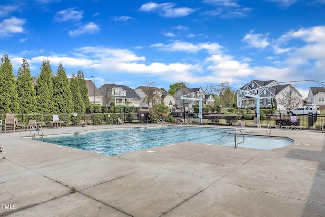 community pool featuring fence, a residential view, and a patio