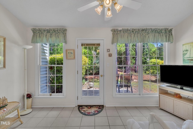 doorway featuring baseboards, ceiling fan, and light tile patterned floors