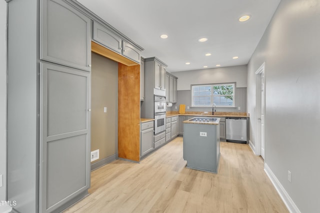 10603 Friendly Neighbor Ln, Raleigh, NC 27614 - kitchen featuring stainless steel appliances, gray cabinets, a sink, light wood-type flooring, and a center island