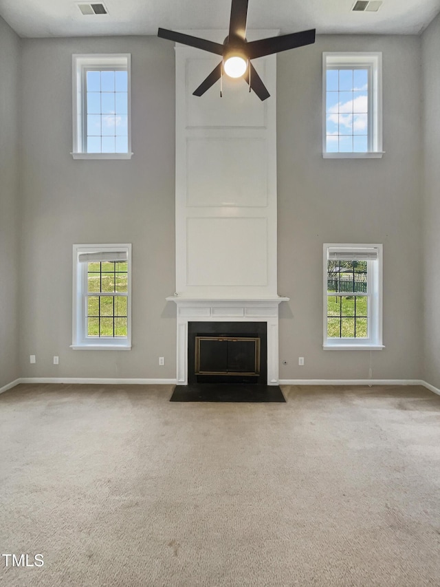 10 Sandy Bluff Ct, Durham, NC 27703 - unfurnished living room with carpet, a towering ceiling, visible vents, a ceiling fan, and a large fireplace