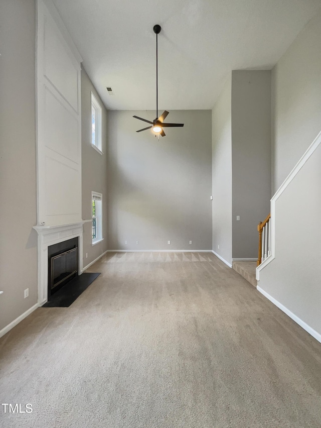 10 Sandy Bluff Ct, Durham, NC 27703 - unfurnished living room with a ceiling fan, stairs, light carpet, a towering ceiling, and baseboards