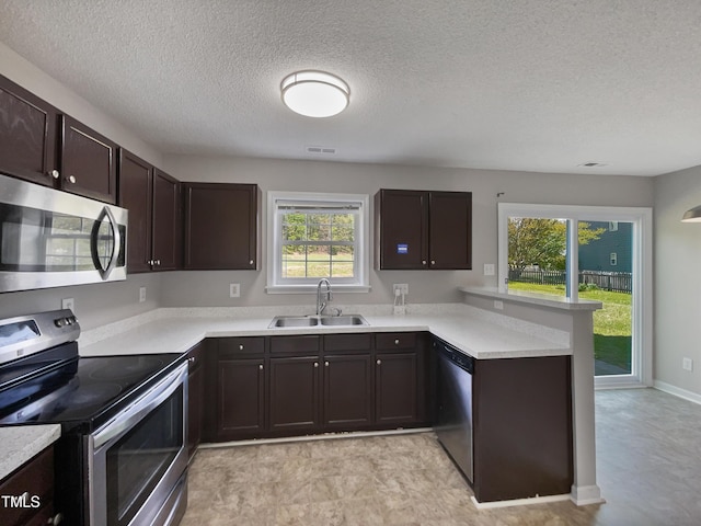 10 Sandy Bluff Ct, Durham, NC 27703 - kitchen featuring dark brown cabinets, a sink, a peninsula, appliances with stainless steel finishes, and visible vents