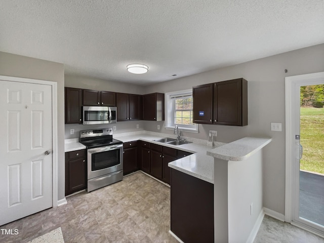 10 Sandy Bluff Ct, Durham, NC 27703 - kitchen featuring dark brown cabinetry, stainless steel appliances, a peninsula, and a sink