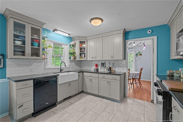 kitchen featuring black dishwasher, a sink, dark countertops, stainless steel range, and a textured ceiling