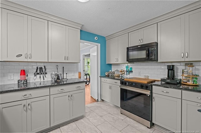 kitchen with black microwave, stainless steel range with electric cooktop, backsplash, dark stone counters, and a textured ceiling