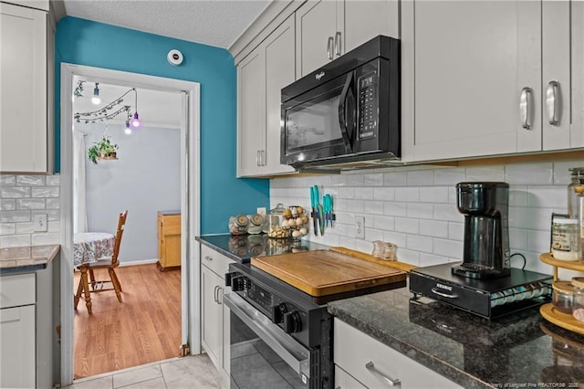 kitchen with black appliances, dark stone countertops, backsplash, a textured ceiling, and white cabinets