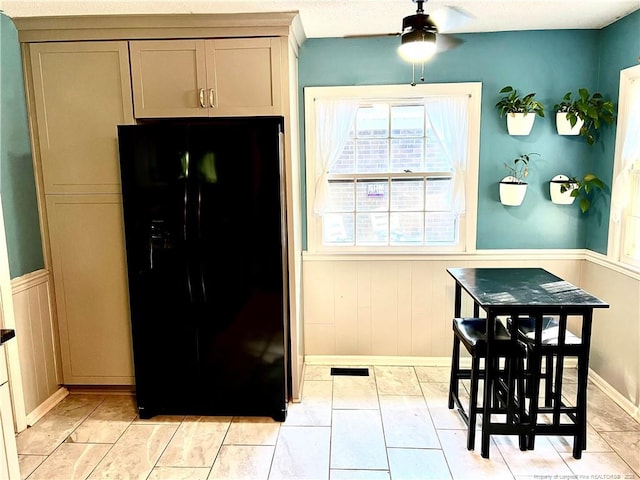 kitchen featuring black fridge with ice dispenser, a wainscoted wall, ceiling fan, and gray cabinetry