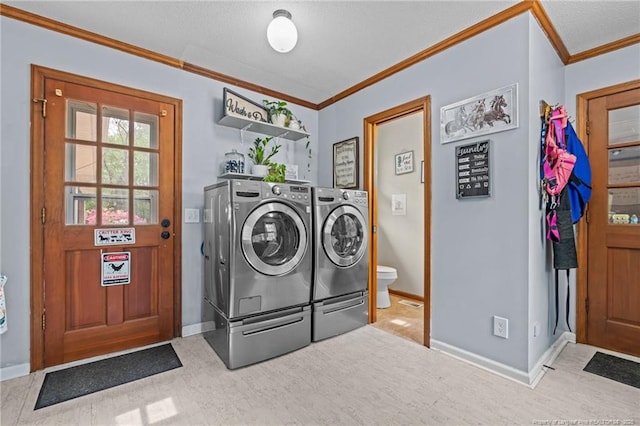 washroom with crown molding, washing machine and dryer, wood finished floors, and baseboards