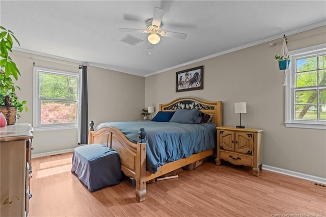 bedroom with light wood-style floors, crown molding, baseboards, and a ceiling fan