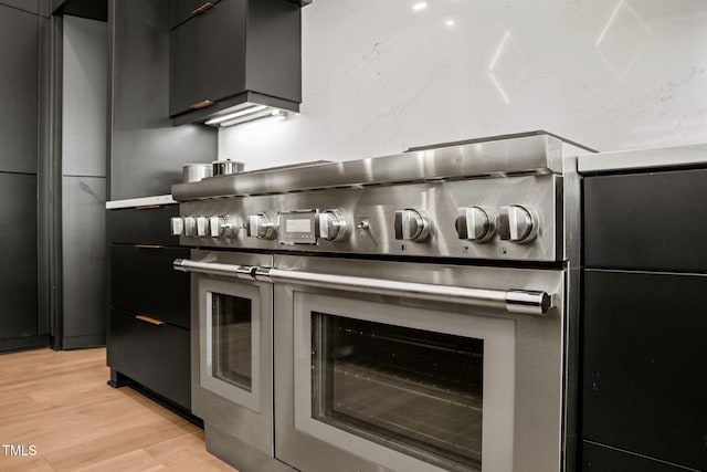 interior space with dark cabinets, modern cabinets, light wood finished floors, and double oven range