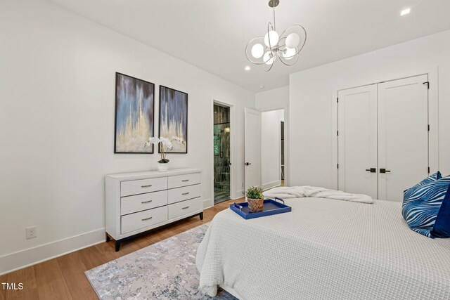 bedroom featuring baseboards, a notable chandelier, wood finished floors, and a closet