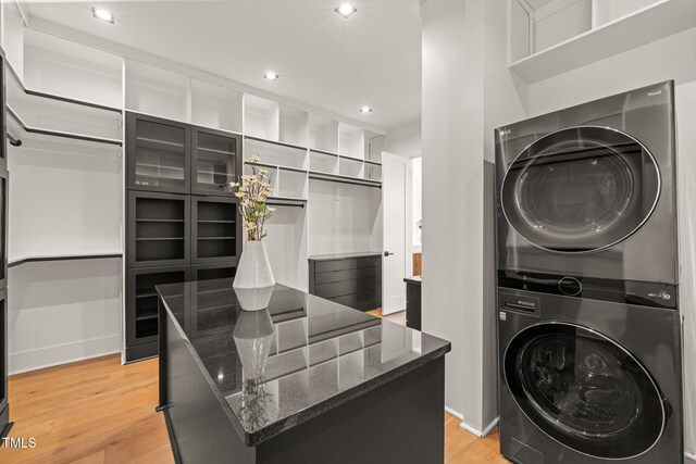 washroom with stacked washer / drying machine, recessed lighting, light wood-style flooring, and laundry area