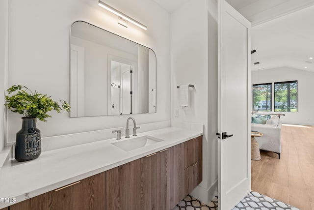 ensuite bathroom with wood finished floors, ensuite bathroom, lofted ceiling, and vanity