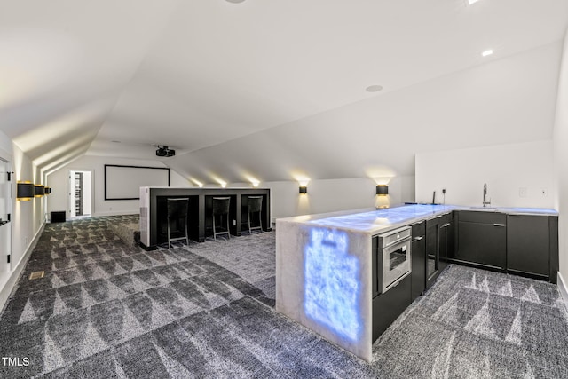 interior space featuring dark colored carpet, a sink, vaulted ceiling, and oven