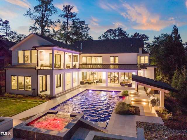 back of house with an outdoor pool, a patio area, a balcony, a standing seam roof, and metal roof