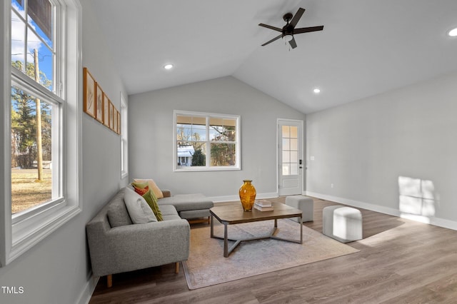 living area with a ceiling fan, wood finished floors, a wealth of natural light, and vaulted ceiling