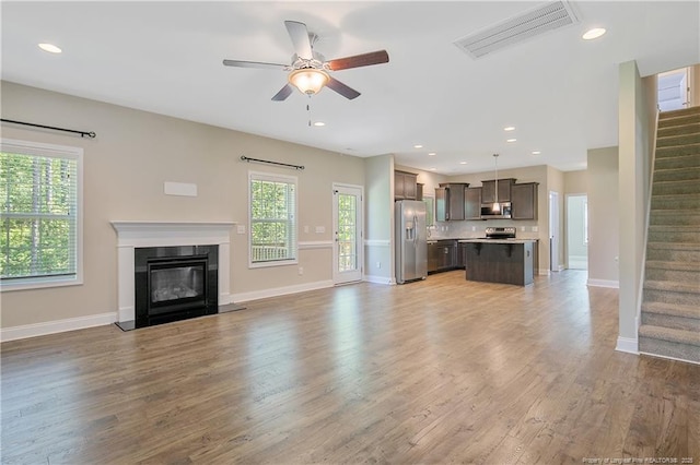 99 Wildlife Bridge Ct, Spring Lake, NC 28390 - unfurnished living room with baseboards, visible vents, light wood-style flooring, and stairway