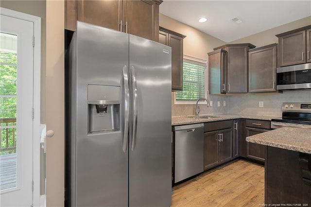 99 Wildlife Bridge Ct, Spring Lake, NC 28390 - kitchen featuring light stone countertops, a sink, stainless steel appliances, decorative backsplash, and light wood-type flooring