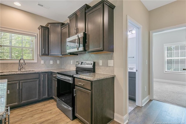99 Wildlife Bridge Ct, Spring Lake, NC 28390 - kitchen with dark brown cabinets, appliances with stainless steel finishes, light stone counters, light wood finished floors, and visible vents