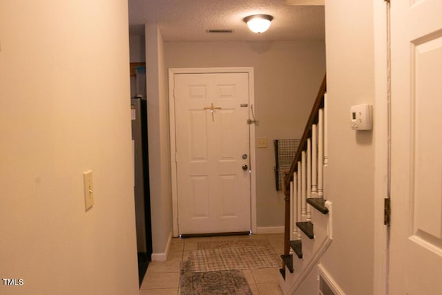 doorway to outside with stairway, a textured ceiling, baseboards, and light tile patterned floors