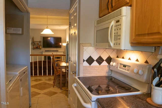 kitchen with brown cabinetry, washer and dryer, tasteful backsplash, and white appliances