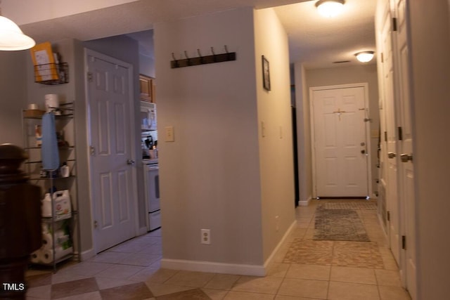 hallway featuring baseboards and light tile patterned floors