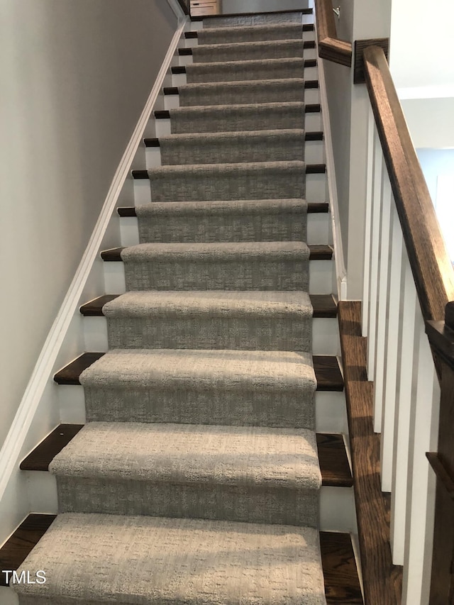 staircase featuring baseboards and wood finished floors
