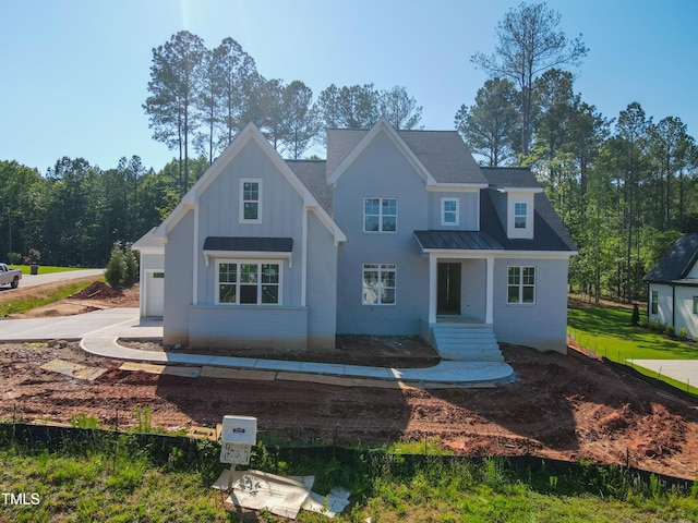 7301 Wexford Woods Ln, Wake Forest, NC 27587 - view of front of property featuring brick siding, board and batten siding, metal roof, a garage, and a standing seam roof
