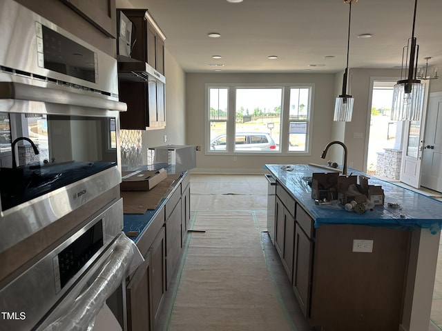 3022 White Rail Dr, Fuquay Varina, NC 27526 - kitchen with double oven, a center island with sink, hanging light fixtures, dark stone countertops, and recessed lighting