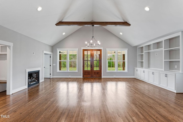 unfurnished living room featuring wood finished floors, a fireplace, baseboards, a notable chandelier, and beam ceiling