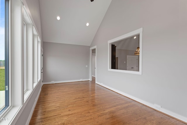 empty room featuring baseboards, wood finished floors, high vaulted ceiling, and recessed lighting