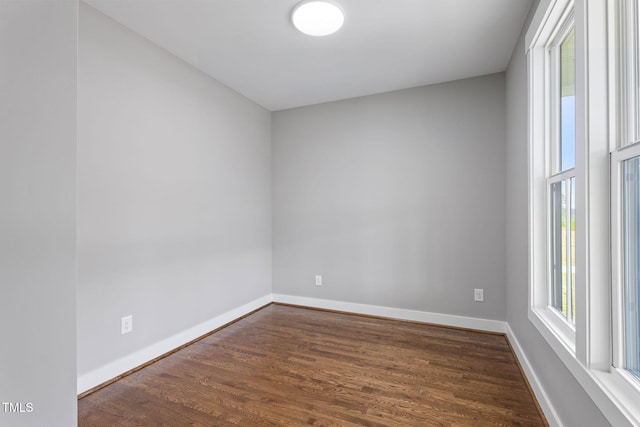 spare room with dark wood-type flooring and baseboards