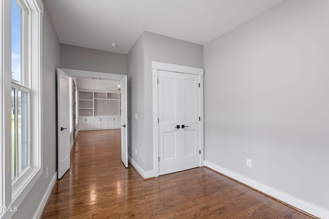 unfurnished bedroom featuring baseboards, a closet, and dark wood-style floors