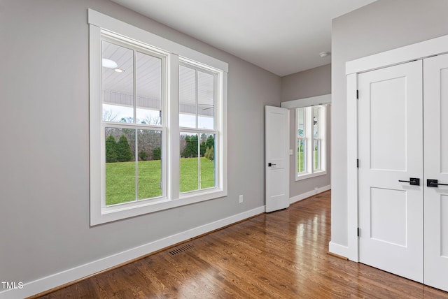 unfurnished bedroom with baseboards, wood finished floors, visible vents, and a closet