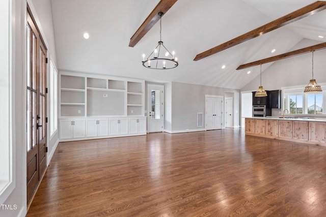 unfurnished living room featuring beamed ceiling, a chandelier, high vaulted ceiling, and a sink