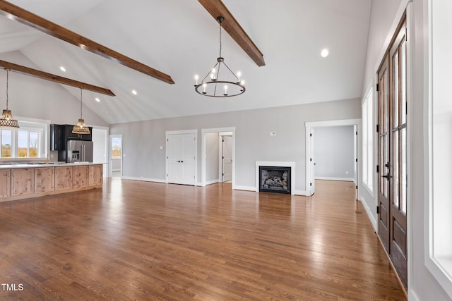 unfurnished living room featuring high vaulted ceiling, an inviting chandelier, beamed ceiling, and recessed lighting