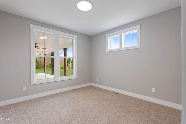 unfurnished room featuring carpet floors, visible vents, and baseboards