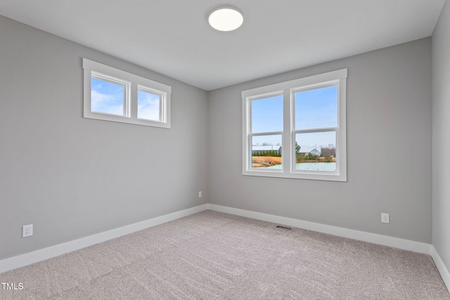 carpeted empty room with visible vents and baseboards