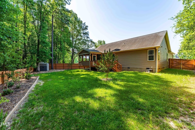 rear view of house with an outdoor structure, a wooden deck, a fenced backyard, a storage unit, and crawl space