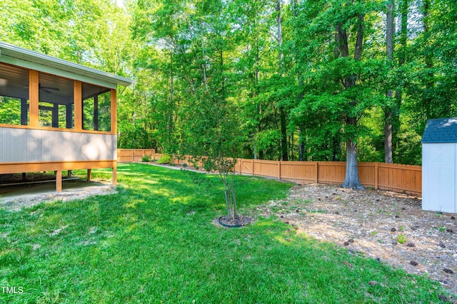view of yard with ceiling fan, a fenced backyard, a sunroom, a storage shed, and an outbuilding