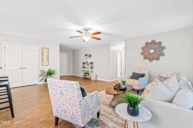 living room with baseboards, ceiling fan, and wood finished floors
