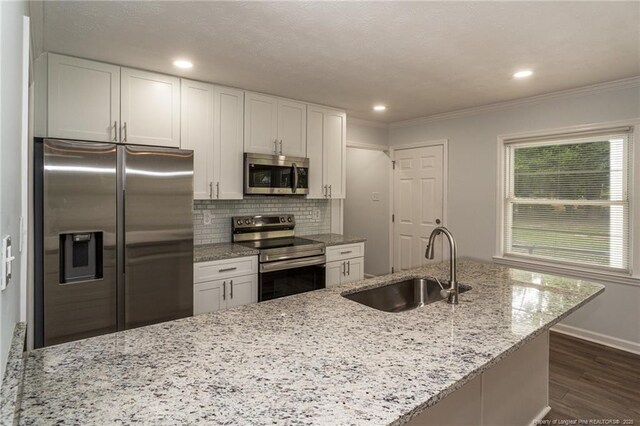 1016 Martindale Dr, Fayetteville, NC 28304 - kitchen with a sink, decorative backsplash, stainless steel appliances, dark wood finished floors, and white cabinetry