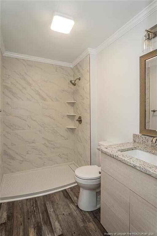 1016 Martindale Dr, Fayetteville, NC 28304 - full bathroom with tiled shower, toilet, wood finished floors, vanity, and ornamental molding