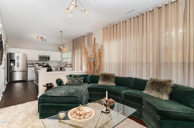 living room with dark wood-type flooring, rail lighting, and visible vents